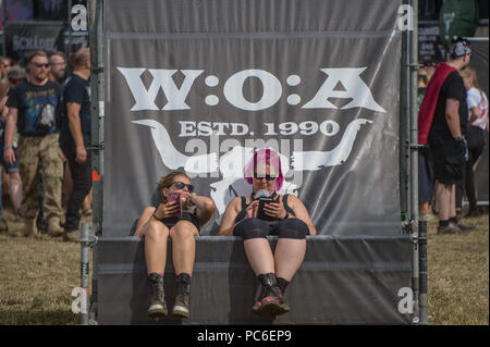 Le Wacken, Allemagne. 06Th Aug 2018. Deux femmes sont en train de bronzer sur une chaise longue sur le Wacken Open Air Festival. La traditionnelle bataille de boue a jusqu'à présent n'a pu avoir lieu, et il y a menace d'un coup de chaleur. Axel Heimken Crédit :/dpa/Alamy Live News Banque D'Images