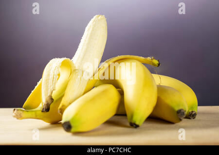 Beaucoup d'entiers et frais, banane jaune et un ouvert avec gradient gris derrière Banque D'Images