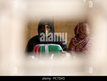 Une femme portant un tricot métallique burqa drapeau Emirati dans l'heritage village à Fujairah. Le village est place aux éléments montrant Emirati la culture. Banque D'Images