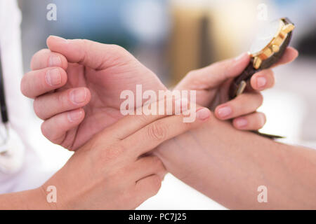 Femme médecin contrôle de patients à l'aide d'impulsion montre-bracelet. Gros plan de la main tenant deux doigts à l'autre poignet personnes pour vérifier le pouls. Banque D'Images