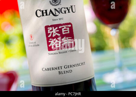 Fermer la vue sur la bouteille et l'étiquette de 'Chinois Changyu Cabernet Gernischt" vin rouge de la région de Ningxia Chine en situation de dégustation jardin en plein air Banque D'Images