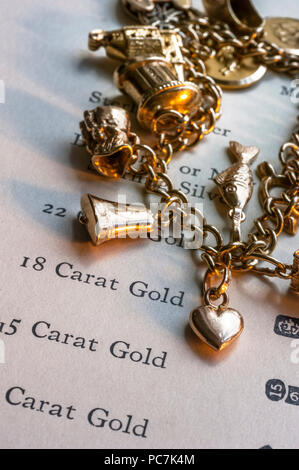 Charmes D'OR SCRAP ANTIQUE GOLD CARAT PURETÉ COEUR 1960 Gold Charm Bracelet & page de la pureté de l'or caractéristiques livre de référence pour l'évaluation de la valeur de rebut Banque D'Images