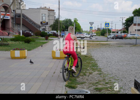 Kiev-sur-Kuban, Russie - 15 mai 2018 : Une jeune femme avec un vélo de montagne jaune est à cheval sur le trottoir. Une promenade en vélo dans le parc. Gi Banque D'Images