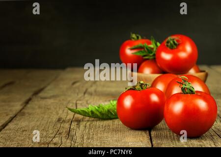 Les tomates fraîches sur une vieille table en bois. Culture des fruits et légumes. Alimentation saine. Matières de la nourriture végétarienne. Vente de tomates Banque D'Images