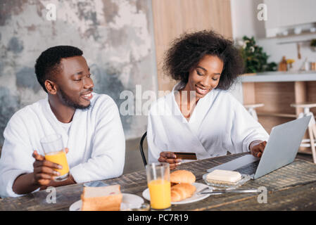 African American couple ayant le petit déjeuner et faire des achats en ligne dans la cuisine Banque D'Images