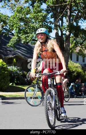 Une jeune femme souriante équitation un vélo à l'eug Parade à Eugene, Oregon, USA. Banque D'Images