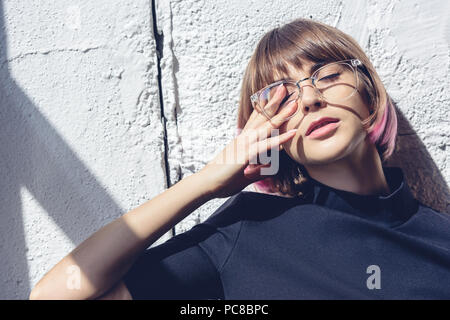 Fille élégant toucher avec les yeux et la main appuyée sur le mur Banque D'Images