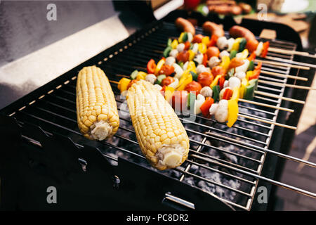 Les épis de maïs et de légumes sur les brochettes cuites sur le gril en plein air Banque D'Images