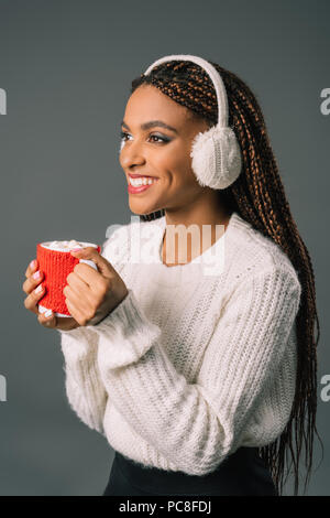 Beautiful smiling african american girl in fur casque antibruit de boire du chocolat chaud avec des guimauves Banque D'Images