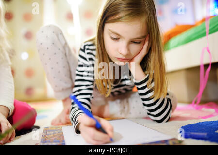 Deux mignonnes petites soeurs d'écrire des lettres ensemble à la maison. Grande sœur aider jeune avec ses devoirs. L'éducation pour les enfants. Banque D'Images