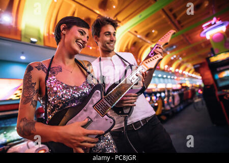 Man and Woman holding guitares jeux jouer à un salon de jeux. Couple de jouer avec lui à une arcade de jeux. Banque D'Images