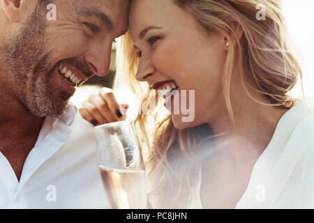 Close up of smiling couple avec leurs têtes de toucher et de rire. Couple aimant avec vin bénéficiant chacun d'autres entreprise. Banque D'Images