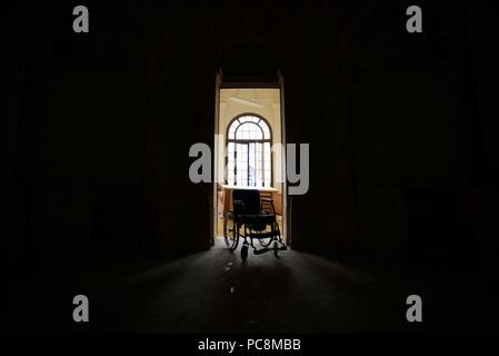 Silhouette d'un fauteuil roulant d'une porte d'un hôpital abandonné avec lumière brillant à partir de l'arrière-plan Banque D'Images