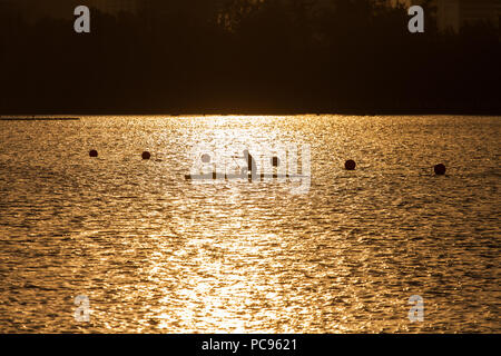 Un homme canoë pendant le coucher du soleil dans une rivière. Banque D'Images