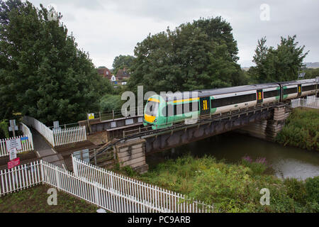 Un train de franchise sud passant sur un passage à niveau sans pilote et pont ferroviaire sur la rivière Tillingham, dans la région de Rye, East Sussex. Banque D'Images