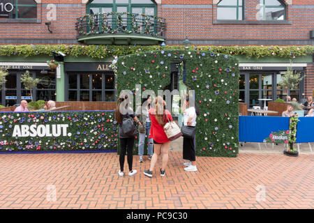 Quatre jeunes femmes se tient en dehors de la terrasse de l'Absolut bar tous un restaraurant dans Brindleyplace, Birmingham, England, UK Banque D'Images