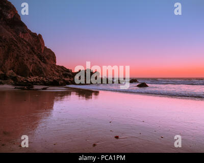 Célèbre Pfeiffer Big Sur plage au coucher du soleil. Falaise rocheuse sur la côte de Californie. Marée basse expose le sable humide avec forte texture dans l'avant-plan. Banque D'Images