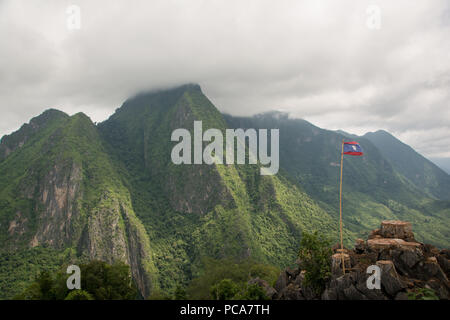 Nong Khiaw vue ci-dessus au Laos Lao PDR avec drapeau et misty montagnes luxuriantes en tbe en arrière. Banque D'Images