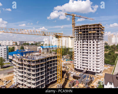 Construction de ville nouvelle zone résidentielle. grues à tour jaune près de bâtiment de plusieurs étages contre fond de ciel bleu Banque D'Images