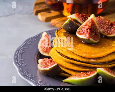 Pile de crêpes à la citrouille avec des figues et du miel et du thé chaud. Arrière-plan de l'alimentation de l'automne sur fond gris bleu Banque D'Images