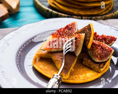 Manger des crêpes à la citrouille avec des figues et du miel avec du thé chaud. Automne fond alimentaire sur table en bois vert Banque D'Images