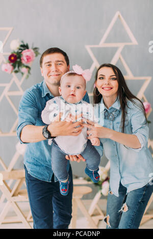 Les parents sont souriants et oscillante de jouer avec leur bébé à la maison joliment décorée.