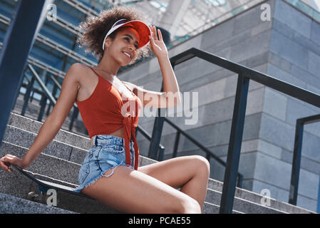 Jeune femme en style libre de pare-soleil dans la rue assis sur des escaliers Banque D'Images