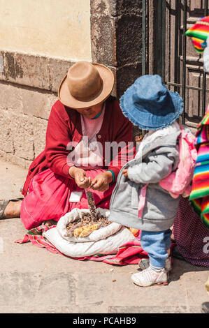 La femme et son bébé dans des vêtements traditionnels de vente de divers épices séchées et des collations, une spécialité locale. Vintage marché sud-américain. Cusco, Pérou Banque D'Images