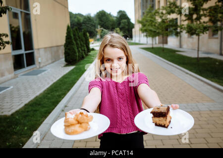 Une jeune fille tenant une assiette de gâteaux. Little cutie. Banque D'Images