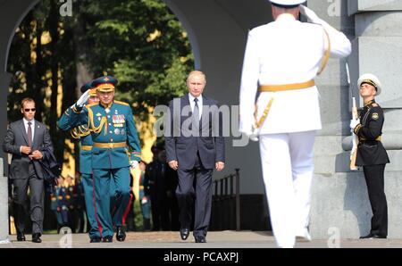 Le président russe Vladimir Poutine, au centre, est salué par la tête de l'École navale Nakhimov Anatoly Minakov, droite, et et le ministre de la défense, Sergueï Choïgou comme il arrive pour une visite à l'École navale Nakhimov pendant les célébrations de la Journée de la Marine, 29 juillet 2018 à Saint-Pétersbourg, en Russie. Banque D'Images
