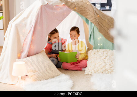 Little girls reading book in kids tente à l'accueil Banque D'Images