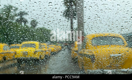 Les gouttes de pluie tombant sur le verre, abstract brouille - stock image mousson de taxi jaune traditionnel de Kolkata, West Bengal, India Banque D'Images