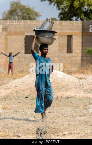 TECHIMAN, GHANA - Jan 15, 2017 : femme ghanéenne non identifié porte sur sa tête des bassins de lavage sur le jour, ce qui est tous les dimanches Banque D'Images