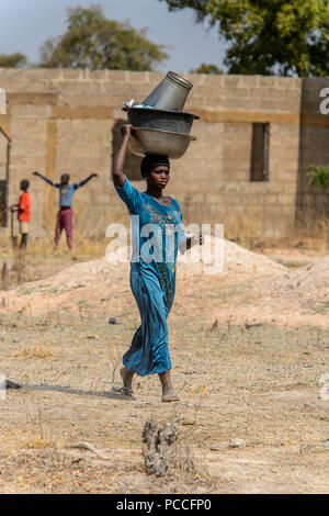 TECHIMAN, GHANA - Jan 15, 2017 : femme ghanéenne non identifié porte sur sa tête des bassins de lavage sur le jour, ce qui est tous les dimanches Banque D'Images