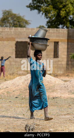 TECHIMAN, GHANA - Jan 15, 2017 : femme ghanéenne non identifié porte sur sa tête des bassins de lavage sur le jour, ce qui est tous les dimanches Banque D'Images