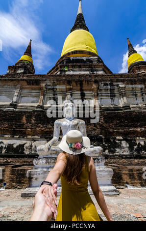 Portrait de belle fille asiatique entraînant son partenaire par la main pour le Wat Yai Chai Mongkol. Le wat est un temple bouddhiste d'Ayutthaya, Thaïlande. Banque D'Images