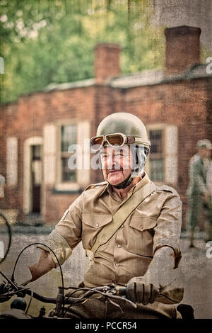 Gros plan sur un homme senior isolé en costume militaire des années 1940, en tant que pilote de l'expédition de guerre sur une moto d'époque, événement d'été de la seconde Guerre mondiale du Black Country Museum, Royaume-Uni. Banque D'Images