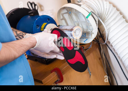 Le processus de fabrication des semelles orthopédiques pour les personnes atteintes de maladies de la jambe, les pieds plats. Close-up de la main d'un homme d'un employé demande instamment une o Banque D'Images