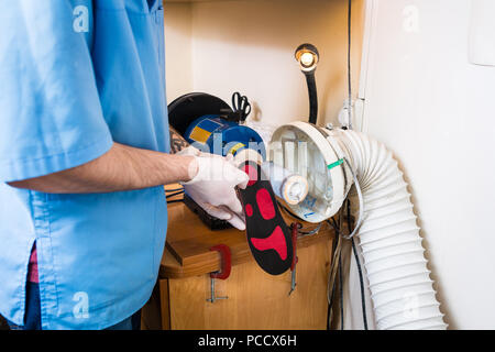 Le processus de fabrication des semelles orthopédiques pour les personnes atteintes de maladies de la jambe, les pieds plats. Close-up de la main d'un homme d'un employé demande instamment une o Banque D'Images