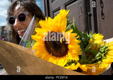 Londres. Hackney. Jeune femme avec des tournesols, Broadway market. Banque D'Images