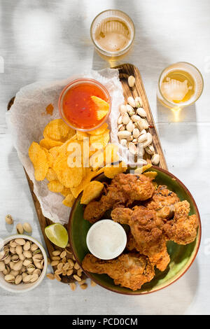 Poulet frit, de la bière et des collations et de la bière sur une surface en bois blanc, vue du dessus Banque D'Images