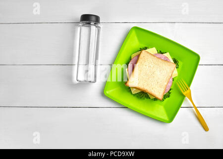 Sandwich au jambon, fromage et une bouteille d'eau sur la table en bois blanc. Dîner santé idée concept. Vue d'en haut. La vie encore. L'espace de copie. télévision lay Banque D'Images