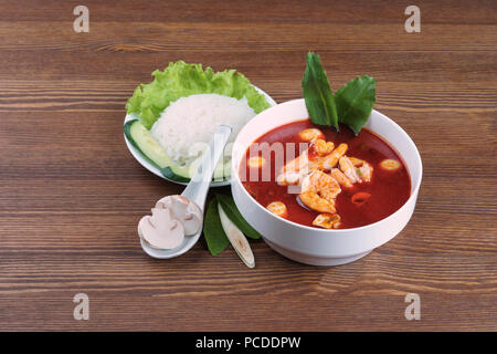 Tom Yum ou tom yam est un type de soupe Thaï aigre et piquante, généralement cuite avec des crevettes. Servi avec du riz et des légumes sur la table en bois brown Banque D'Images