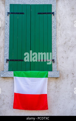 Drapeau national italien suspendu à une fenêtre verte fermé les volets. Banque D'Images