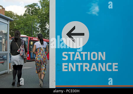 Deux femmes passent devant un panneau avec la flèche indiquant la route à l'entrée de la station Ealing, Ealing, London, England Banque D'Images