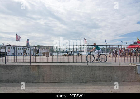 STOCKHOLM, Suède - 11 juillet 2018 : les cyclistes et les touristes près de ferry bateaux d'excursion avec des nuages blancs le 11 juillet 2018 à Stockholm, en Suède. Banque D'Images