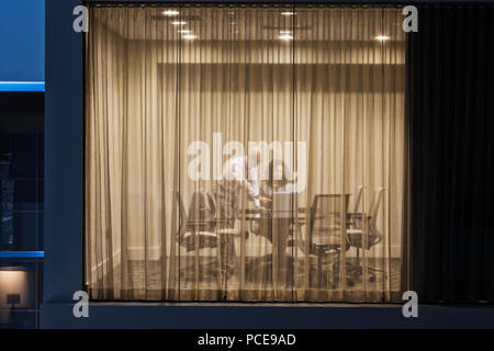 Une vue de la nuit à la recherche d'une salle de conférence avec deux businessman working at conference table. Banque D'Images