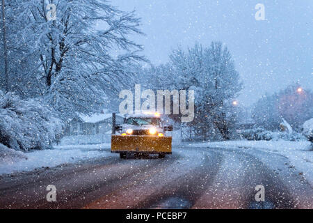 Un chasse-neige avec phares sur la conduite dans un paysage de neige par une nuit d'hiver Banque D'Images