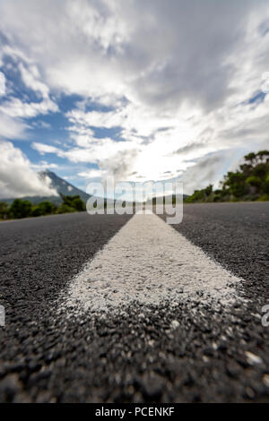 Marques de séparation blanc dans la ligne droite EN3 route longitudinale au nord-est du mont Pico et la silhouette de la montagne Pico le long de , l'île de Pico, Açores Banque D'Images