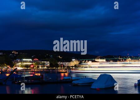 Grand bateau de croisière sur le lac de Zurich dans la nuit avec de l'eau et l'éclairage bleu ciel nuageux Banque D'Images